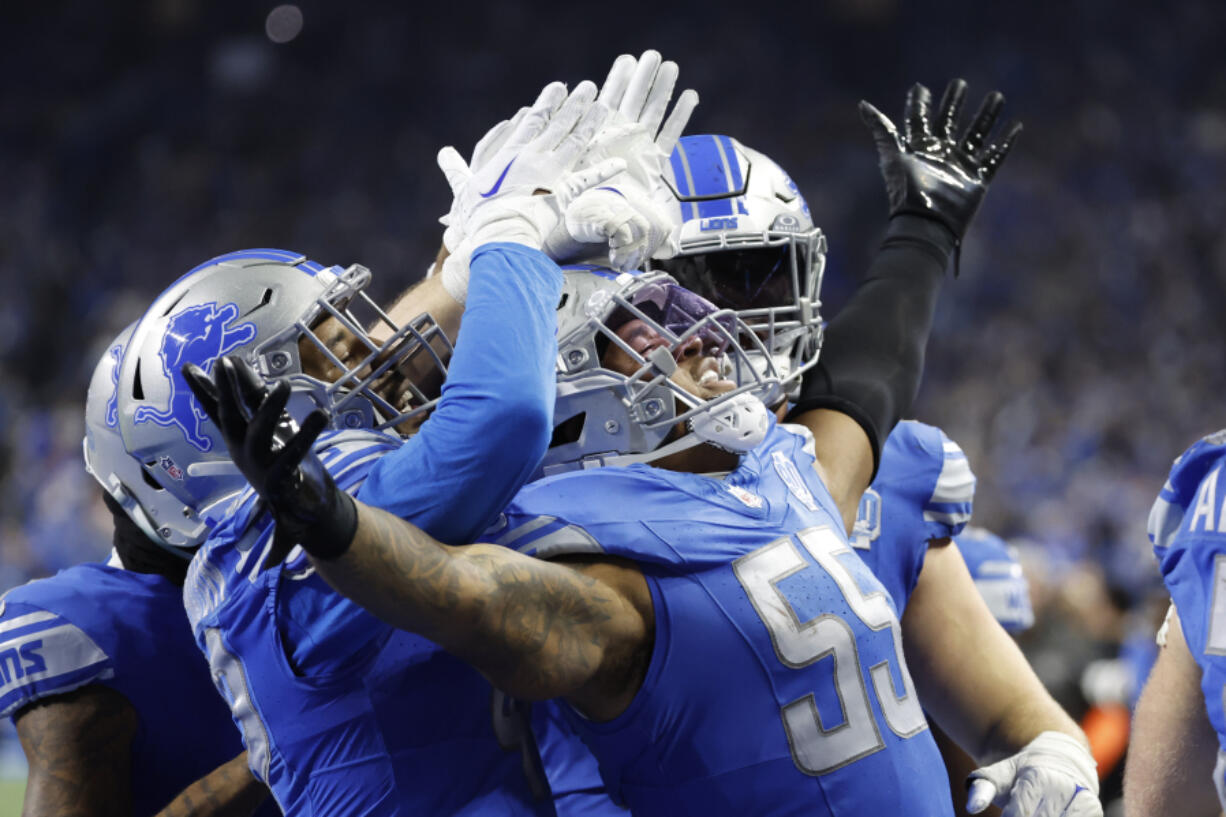 Detroit Lions linebacker Derrick Barnes (55) receives congratulations from teammates after he makes an interception in the fourth quarter against the Tampa Bay Buccaneers during an NFL divisional round playoff football game Sunday, Jan. 21, 2024, in Detroit.