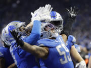 Detroit Lions linebacker Derrick Barnes (55) receives congratulations from teammates after he makes an interception in the fourth quarter against the Tampa Bay Buccaneers during an NFL divisional round playoff football game Sunday, Jan. 21, 2024, in Detroit.