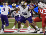 FILE - Washington offensive lineman Troy Fautanu (55) blocks for running back Dillon Johnson (7) who takes a handoff from quarterback Michael Penix Jr. (9) in the first half during an NCAA college football game against Arizona Sept. 30, 2023, in Tucson, Ariz. Fautanu and the Huskies&#039; offensive line paved the way for No. 2 Washington to make the College Football Playoff. They are scheduled to face No. 3 Texas in the Sugar Bowl, Monday, Jan. 1, 2024.