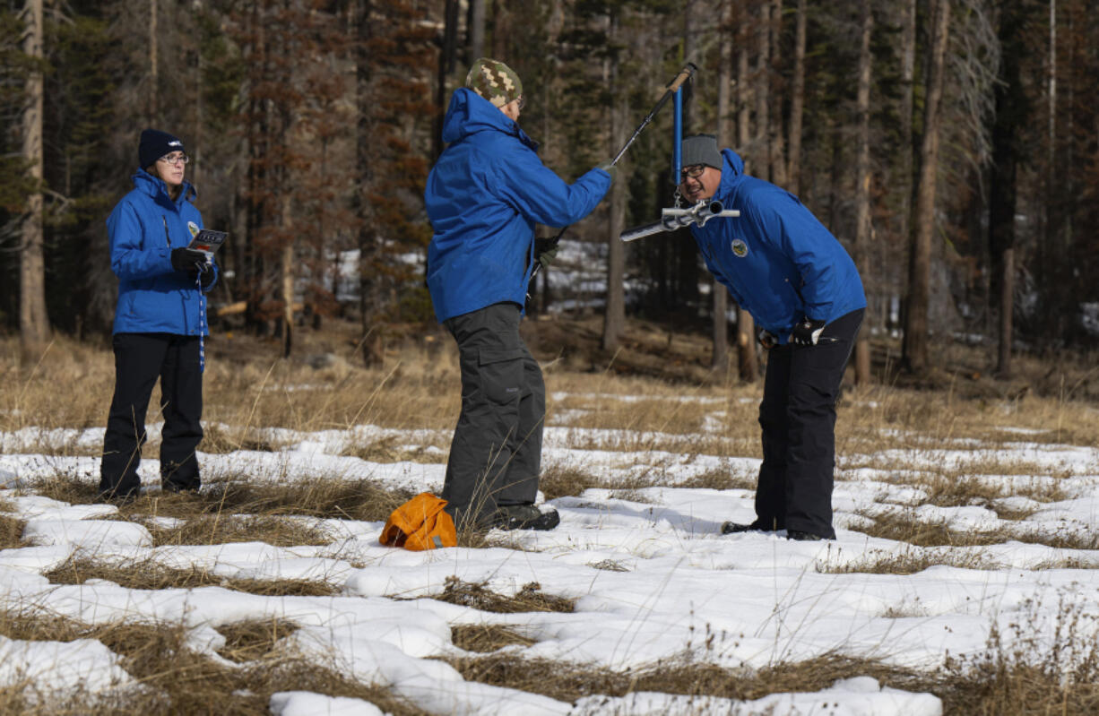 FILE - Sean de Guzman, right, snow survey manager at the California Department of Water Resources, conducts the first snow survey of the season with his team at Phillips Station, Calif., on Tuesday, Jan. 2, 2024. Once regularly snowbound river basins across the globe are increasingly seeing their snowpack shrink and climate change is to blame, a new study found.