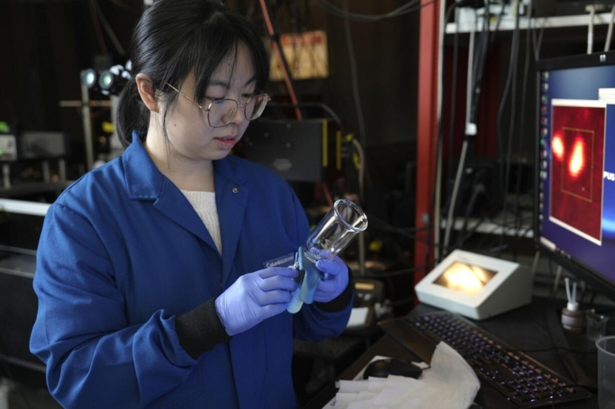 Naixin Qian, a Columbia physical chemist, places a sample containing nanoplastics, microscopic plastic pieces, under a microscope in New York on Monday, Jan. 8, 2024. A new study found the average liter of bottled water has nearly a quarter million invisible pieces of nanoplastics, detected and categorized for the first time by a microscope.