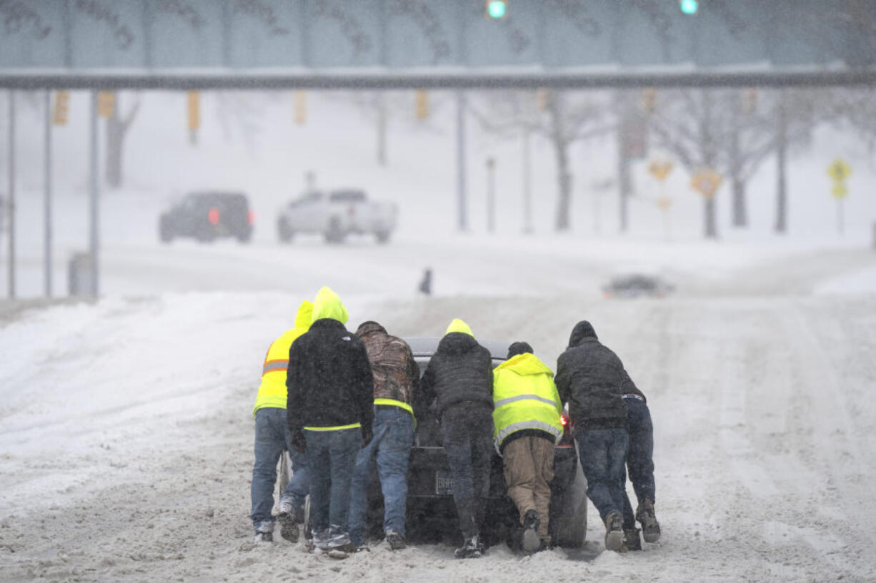 FILE - People help a driver out after his rear-wheel drive vehicle got stranded after a winter storm in Nashville, Tenn., Jan. 15, 2024. While the U.S. is shivering through bone-chilling cold, most of the rest of world is feeling unusually warm weather. Scientists Tuesday, Jan. 16, say that fits with what climate change is doing to Earth.