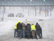 FILE - People help a driver out after his rear-wheel drive vehicle got stranded after a winter storm in Nashville, Tenn., Jan. 15, 2024. While the U.S. is shivering through bone-chilling cold, most of the rest of world is feeling unusually warm weather. Scientists Tuesday, Jan. 16, say that fits with what climate change is doing to Earth.