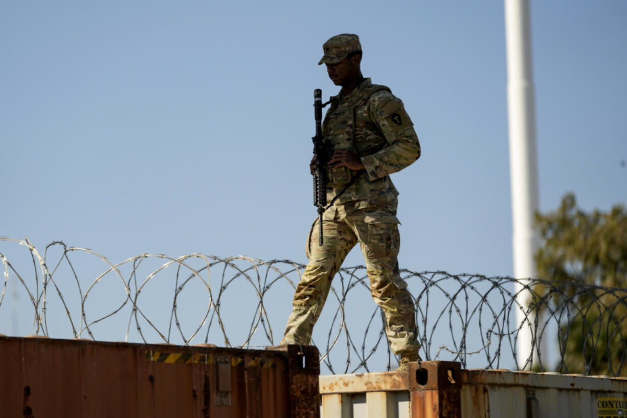 A Guardsman walks over rail cars with concertina wire Jan. 3 along the Texas-Mexico border in Eagle Pass, Texas.