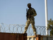 A Guardsman walks over rail cars with concertina wire Jan. 3 along the Texas-Mexico border in Eagle Pass, Texas.