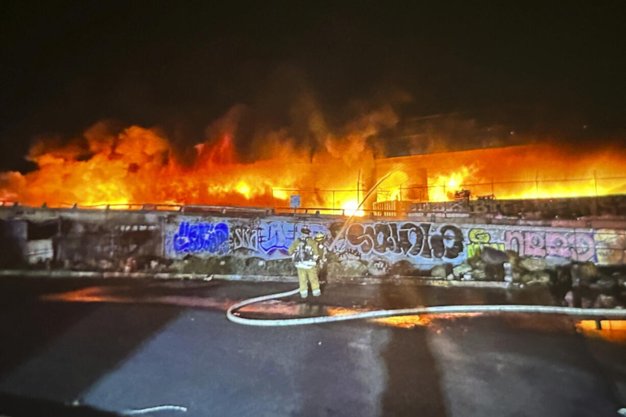 FILE- This photo provided by the California Department of Transportation shows an early morning fire along Interstate 10 near downtown Los Angeles, Saturday, Nov. 11, 2023. Since an arson fire damaged a key Los Angeles freeway, the state has hired security guards to watch out for smoke and other trouble at three other sites deemed equally risky under Interstate 10.