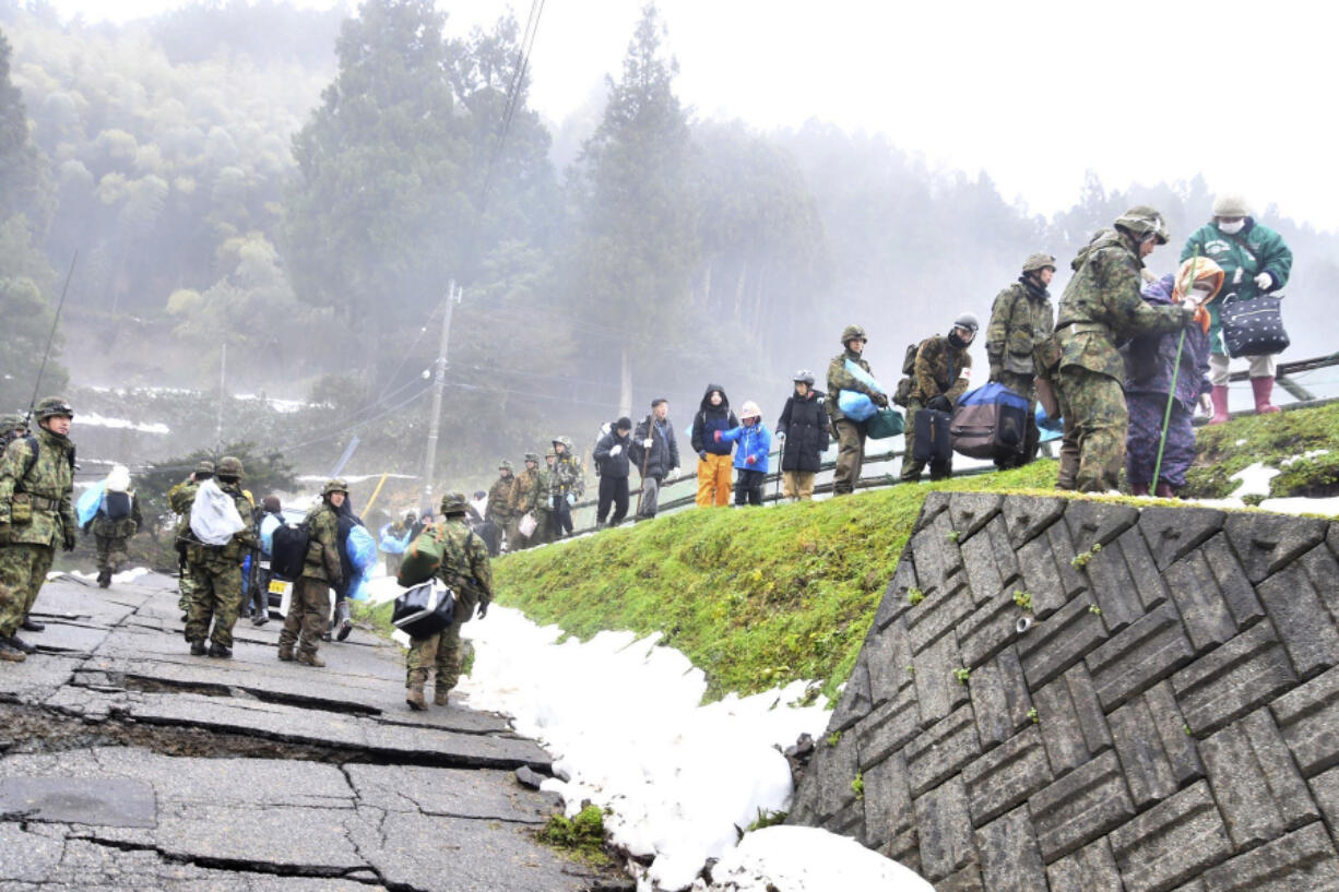 In this photo provided by Japanese Ministry of Defense, residents are evacuated with the help of Japanese Self Defense Force members, as their district was isolated by the earthquakes, in Wajima, Ishikawa prefecture, Japan, Wednesday, Jan. 3, 2024.