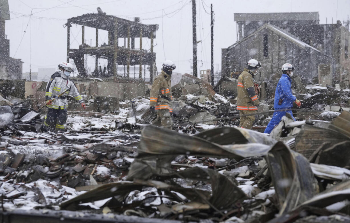 Snow falls as rescuers conduct a search operation around a burnt market in Wajima, Ishikawa prefecture, Japan Sunday, Jan. 7, 2024. A major earthquake slammed western Japan on Jan. 1, killing scores of people, toppling buildings and setting off landslides.