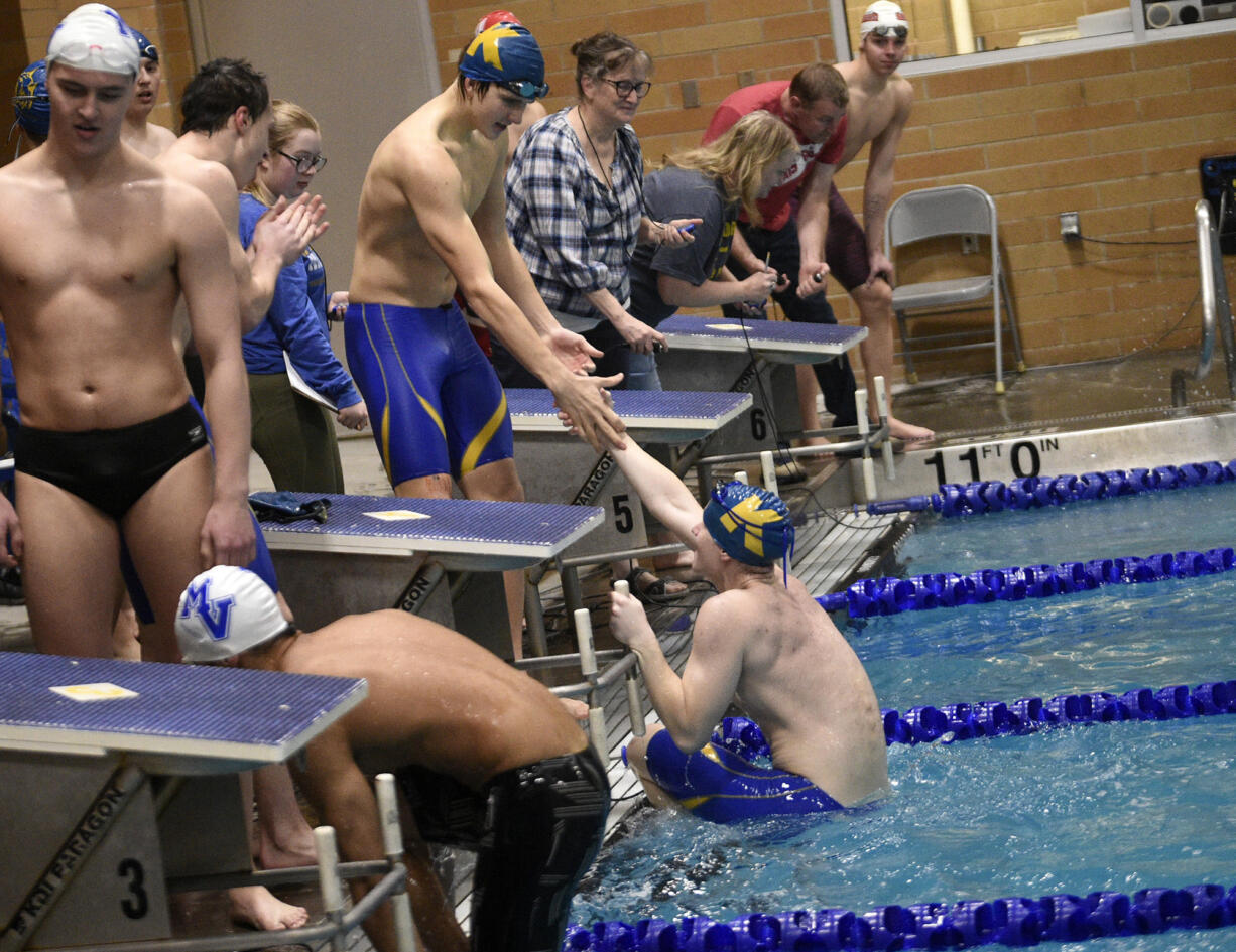 Harry Eugenis of Kelso is helped out of the pool after swimming the anchor leg in Kelso's win in the 200 freestyle relay at the Kelso Invitational swim meet at Kelso High School on Saturday, January 20, 2024.