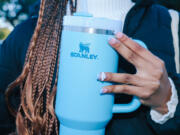 Kimora Johnson poses for a portrait with a Stanley Cup branded water bottle outside her high school in Culver City. She recently purchased the cup, which has been selling out at retailers, from Urban Outfitters.