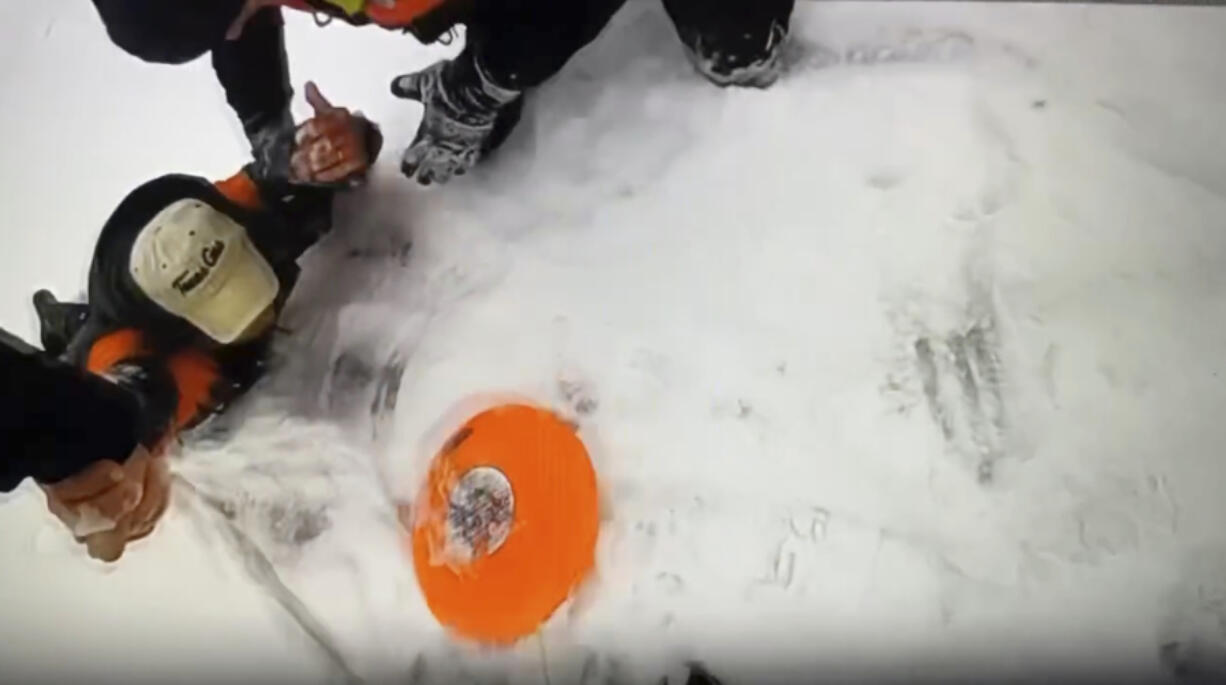 In this image taken from video provided by Michigan State Police, officers work to extricate a man from the waters of frozen Arbutus Lake in Grand Traverse County, Mich., Thursday, Jan. 18, 2024. The man was rescued after a quick-thinking state police officer used the stranded man&rsquo;s dog to get rescue equipment to him and pull the man to safety in a rescue captured on video.