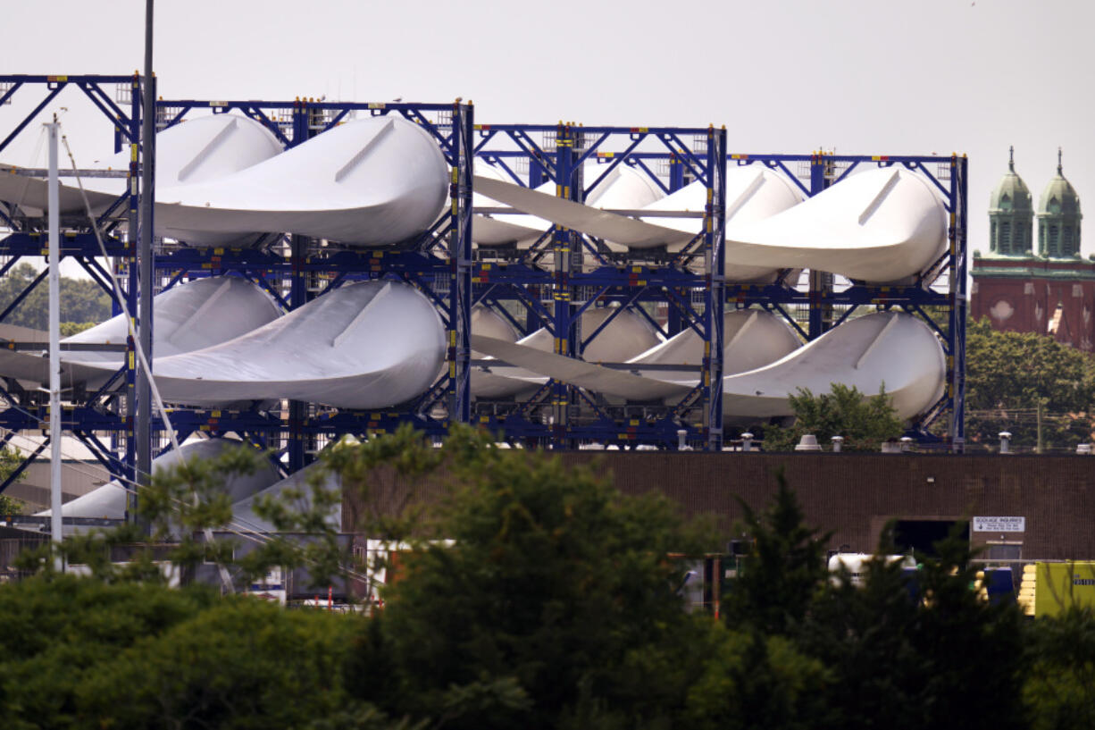 FILE - Giant wind turbine blades for the Vineyard Winds project are stacked on racks in the harbor, July 11, 2023, in New Bedford, Mass. The joint owners of the Vineyard Wind project, Avangrid and Copenhagen Infrastructure Partners, announced Wednesday, Jan. 3, 2024, the first electricity from one turbine at what will be a 62-turbine wind farm 15 miles (24 kilometers) off the coast of Massachusetts.