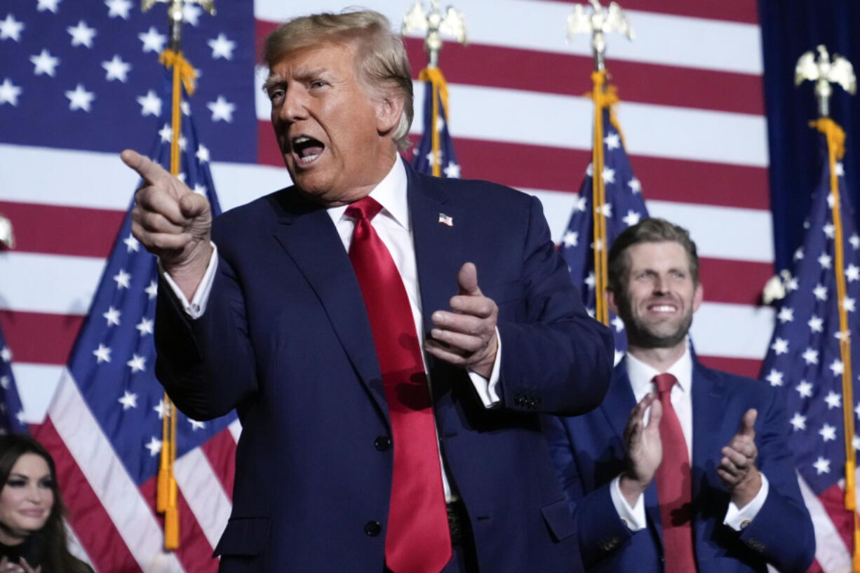 Republican presidential candidate former President Donald Trump points to the crowd, accompanied by his son, Eric, at a caucus night party in Des Moines, Iowa, Monday, Jan. 15, 2024.