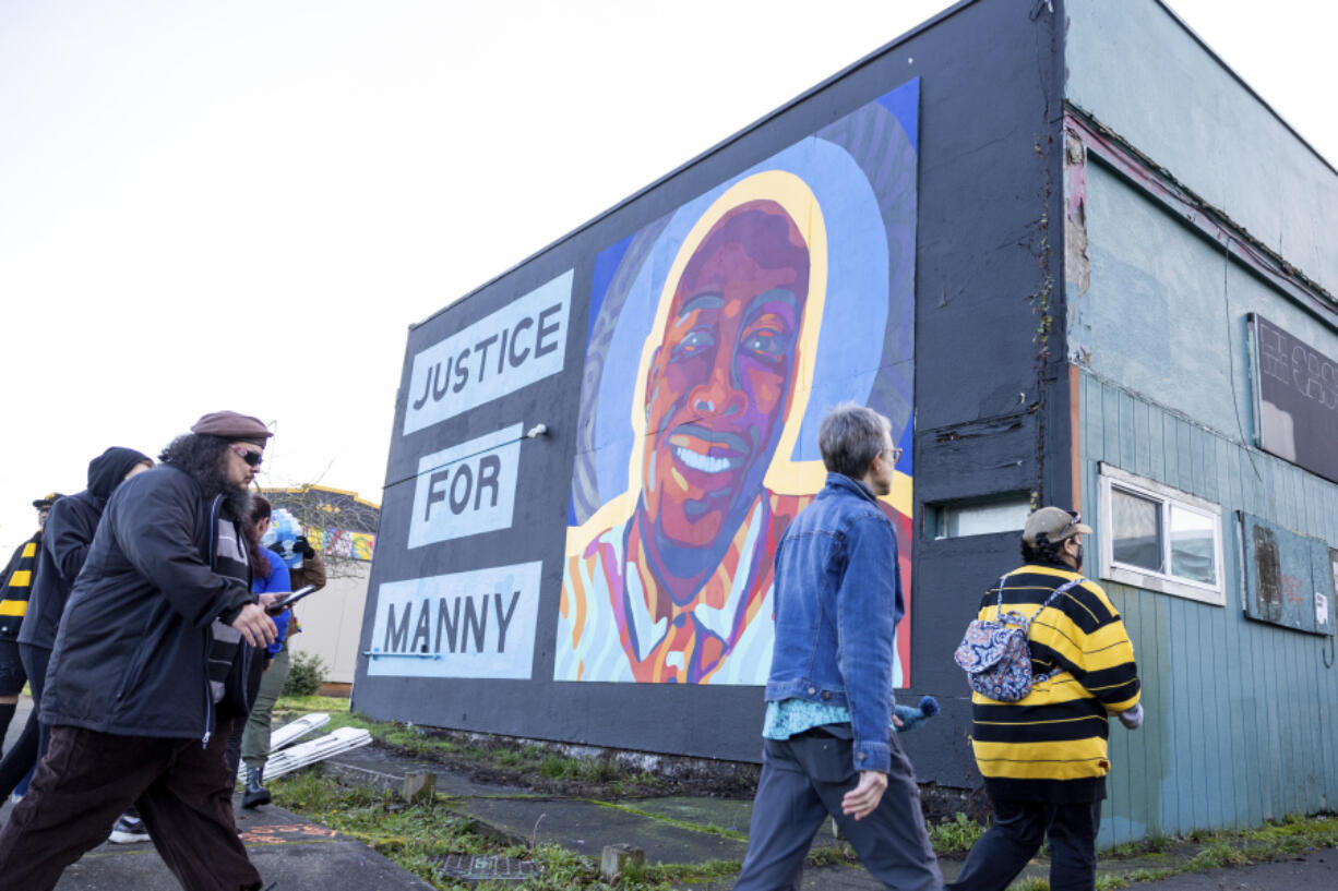 FILE - Protesters walk by a mural of Manny Ellis after the verdict is read during the trial of three Tacoma police officers in the death of Ellis, Dec. 21, 2023, at Pierce County Superior Court in Tacoma, Wash. Three Washington state police officers who were cleared of all criminal charges last month in the 2020 death of Ellis will each receive $500,000 to leave the Tacoma Police Department, according to documents released, Tuesday, Jan. 16, 2024.
