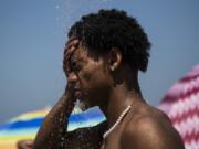 A man cools off in a shower at Ipanema beach in Rio de Janeiro, Brazil, on Sept. 24. Calculations released by several science agencies Friday say that global average temperatures for 2023 shattered existing heat records.