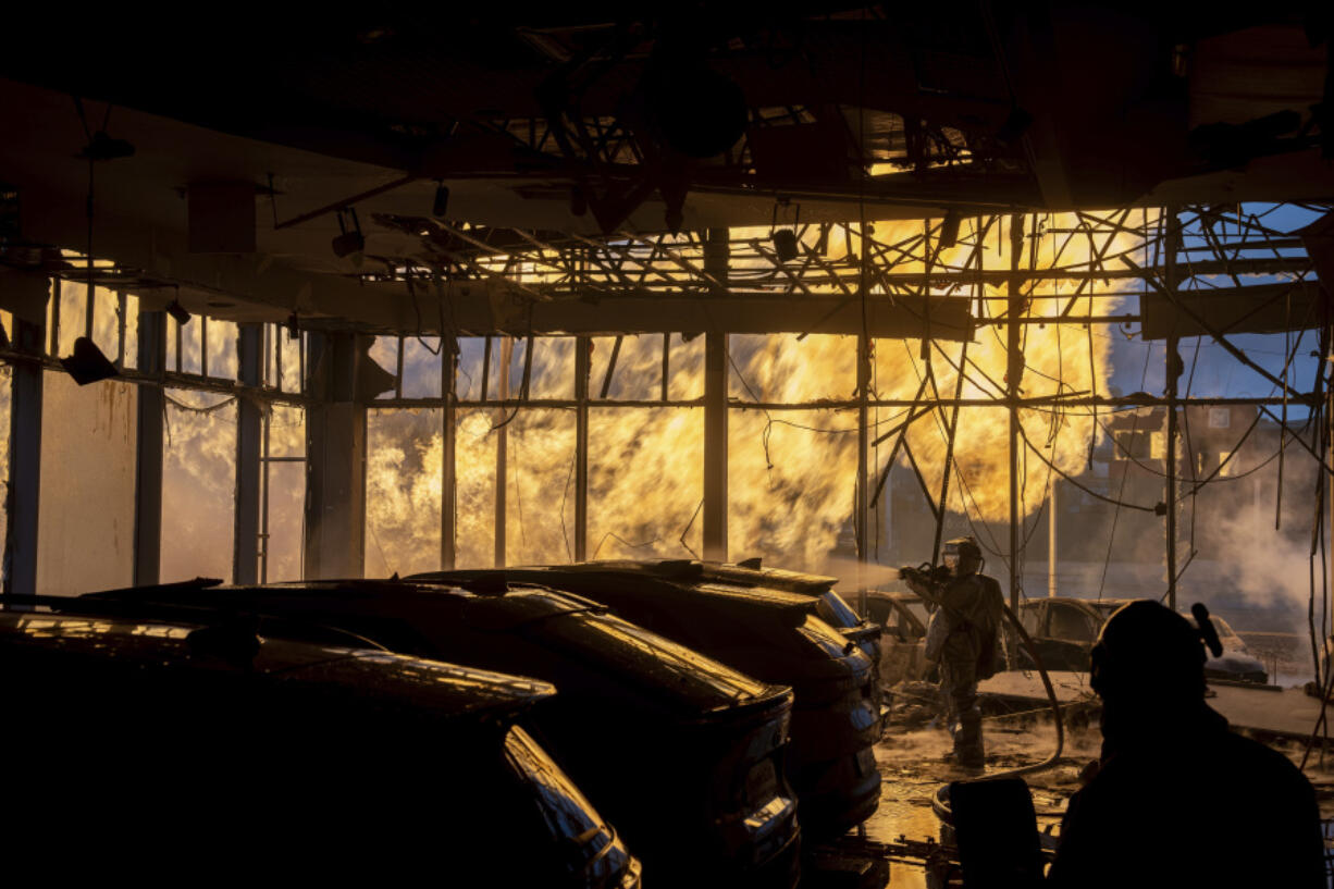 A firefighter works to extinguish a fire in a car shop near a gas pipe line damaged by a Russian rocket attack,  in Kyiv, Ukraine, Tuesday, Jan. 2, 2024.