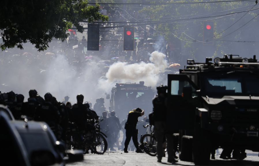 FILE - Smoke rises as police clash with protester during a Black Lives Matter protest near the Seattle Police East Precinct headquarters, July 25, 2020, in Seattle. Seattle has agreed to pay $10 million to 50 demonstrators who sued over the police department&rsquo;s heavy-handed response to racial justice protests in 2020, attorneys for both sides said Wednesday, Jan. 24, 2024. (AP Photo/Ted S.