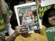 FILE - A George Mason University fan holds up the cover of Sports Illustrated magazine at a send off for the team, Wednesday, March 29, 2006, in Fairfax, Va. The publisher of Sports Illustrated has notified employees it is planning to lay off a significant portion &mdash; possibly all &mdash; of the outlet&rsquo;s staff after its license to use the iconic brand&rsquo;s name in print and digital was revoked. In an email to employees Friday morning, Jan. 19, 2024, the Arena Group, which operates Sports Illustrated and related properties, said that Authentic Brands Group has revoked its marketing license.