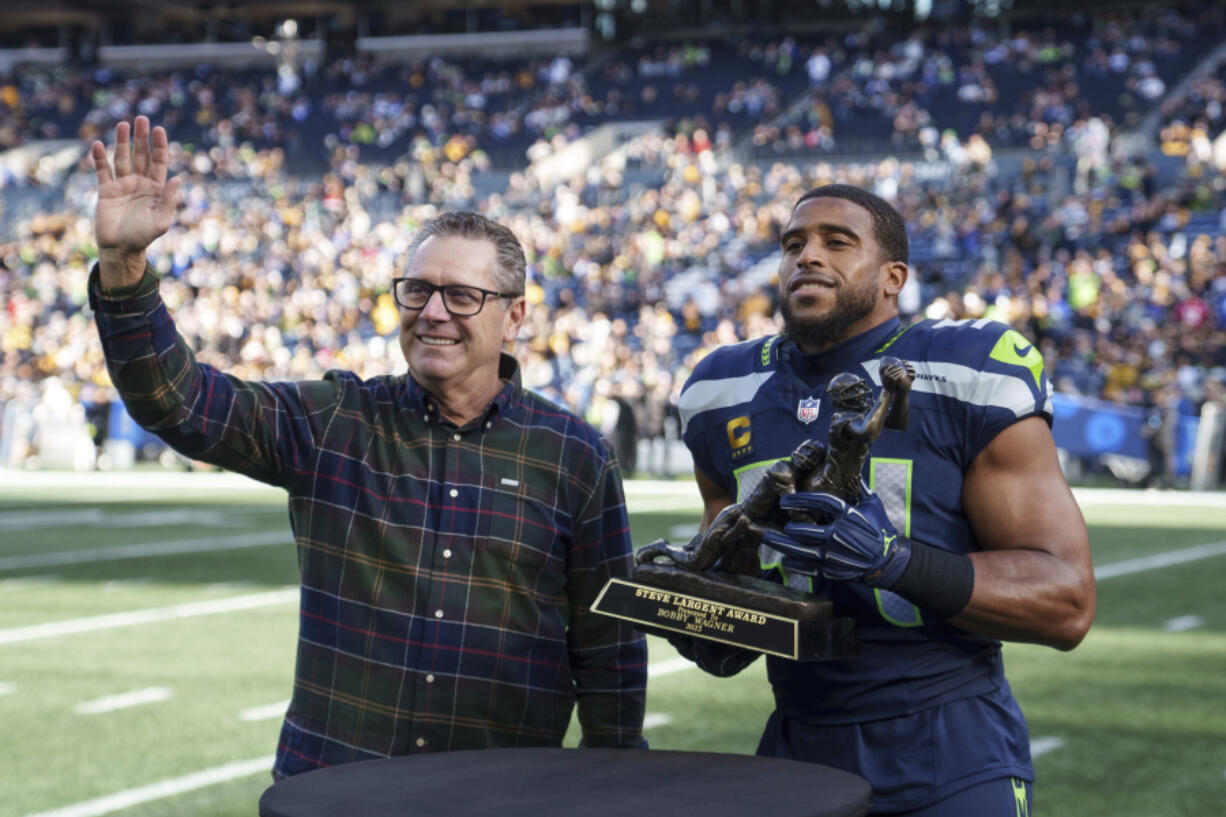 Seattle Seahawks linebacker Bobby Wagner, right, is presented with the Steve Largent award by former Seattle Seahawks player Steve Largent before an NFL football game against the Pittsburgh Steelers, Sunday, Dec. 31, 2023, in Seattle. The Steelers won 30-23.