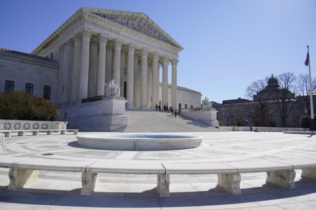 FILE - People stand on the steps of the U.S. Supreme Court, Feb.11, 2022, in Washington. The Supreme Court is taking up challenges by commercial fishermen to a fee requirement that could achieve a long-sought goal of business and conservative interests, limiting a wide range of government regulations. Billions of dollars are potentially at stake.