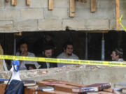 FILE - Hasidic Jewish students sit behind a breach in the wall of a synagogue that led to a tunnel dug by the students, Monday, Jan. 8, 2024, in New York.