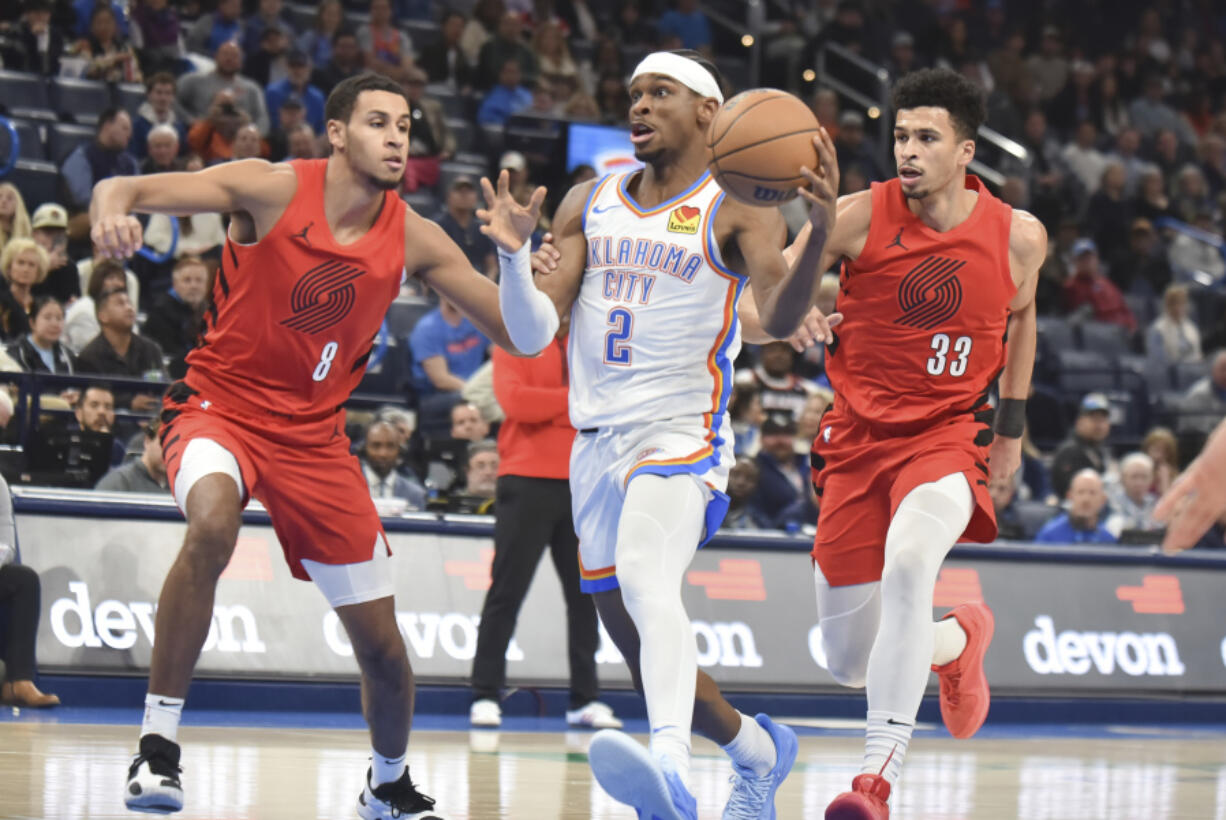 Oklahoma City Thunder Shai Gilgeous-Alexander (2) drives past Portland Trail Blazers forwards Kris Murray (8) and Toumani Camara (33) in the second half of an NBA basketball game, Thursday, Jan. 11, 2024, in Oklahoma City.