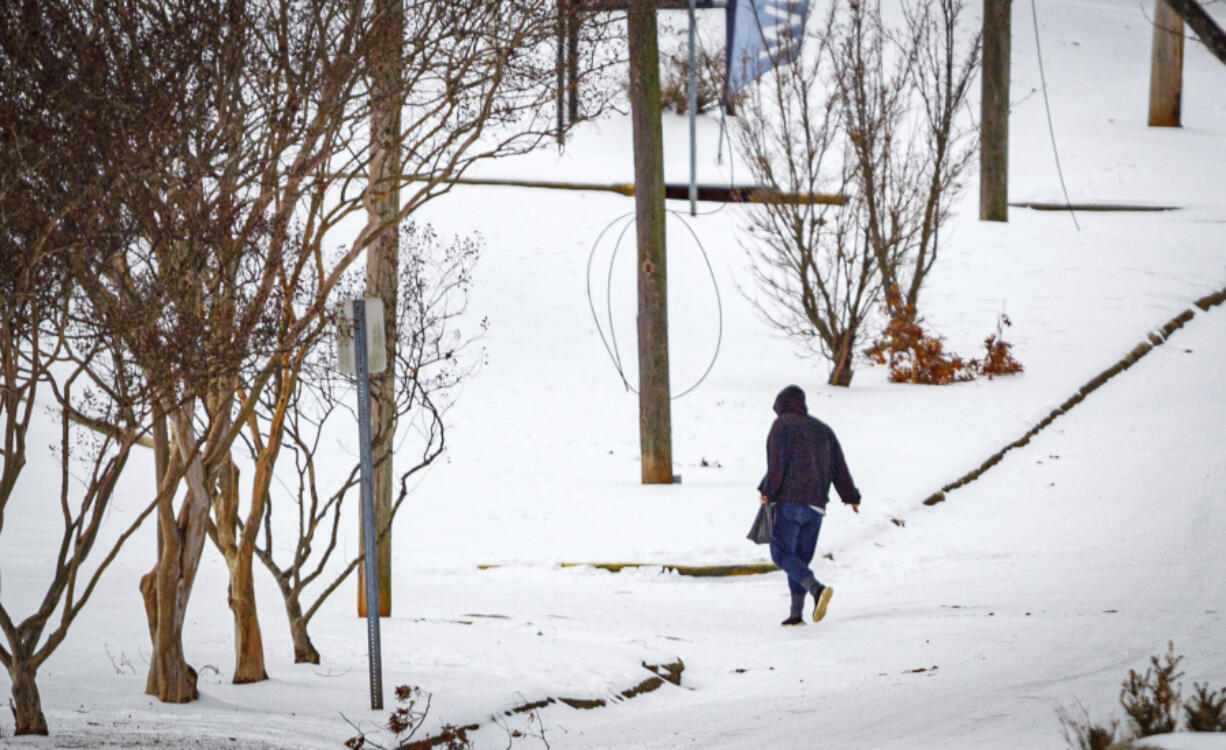 A person crosses in icy conditions in snow while walking over West Tennessee Street, Thursday, Jan. 18, 2024, in downtown Florence, Ala.