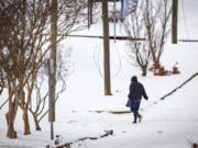 A person crosses in icy conditions in snow while walking over West Tennessee Street, Thursday, Jan. 18, 2024, in downtown Florence, Ala.