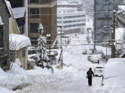 A pedestrian walks down a steep downtown street in Juneau, Alaska, on Tuesday, Jan. 23, 2024. Juneau has received more than 55 inches of snow so far in January, far above the normal level of 24.5 inches, according to the National Weather Service.