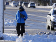 A pedestrian bundles up as she crosses the street in Buffalo Grove, Ill., Sunday, Jan. 14, 2024. A wind chill warning is in effect as dangerous cold conditions continue in the Chicago area. (AP Photo/Nam Y.