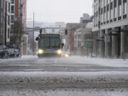 A bus drives on SE Belmont Street in the snow on Saturday, Jan. 13, 2024, in Portland, Ore.