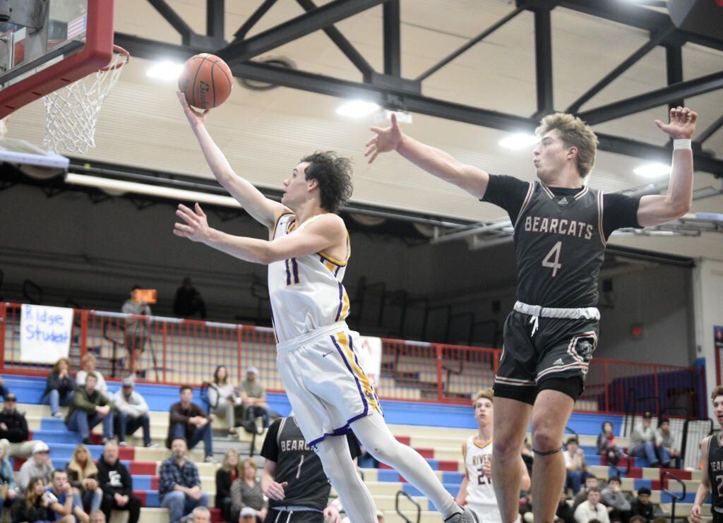 Columbia River’s John Reeder, left, soars past W.F. West’s Gage Brumfield for a layup during a Class 2A District 4 boys basketball semifinal game on Tuesday, Feb. 13, 2024, at Mark Morris High School.