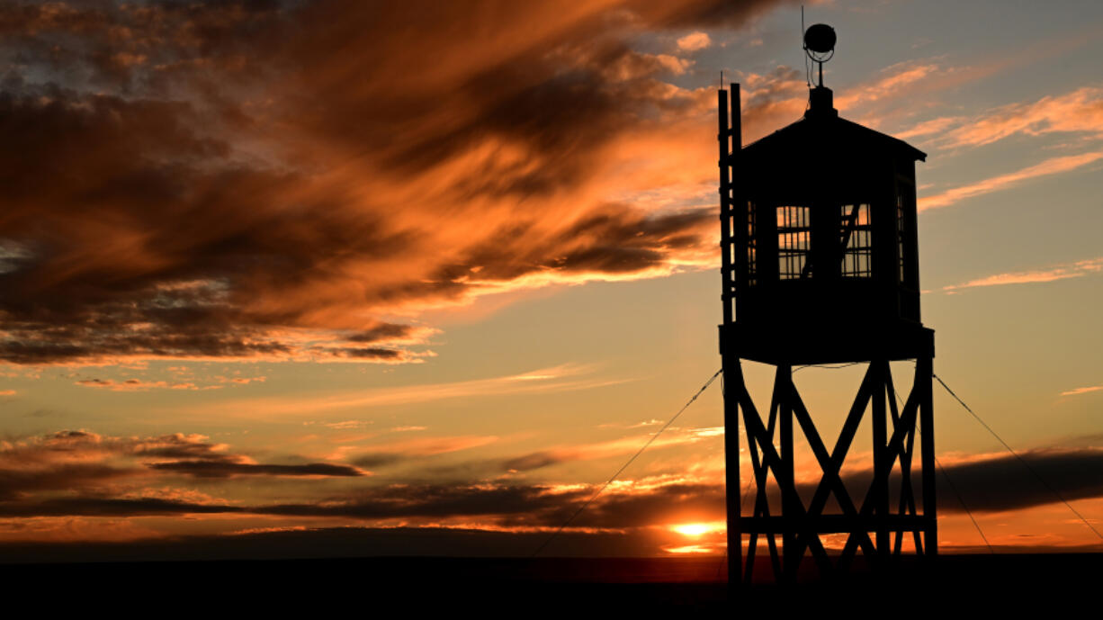 The sun sets behind a replica of the old guard tower at The Amache National Historic Site on Nov. 14, 2022, in Granada, Colo. (Helen H.