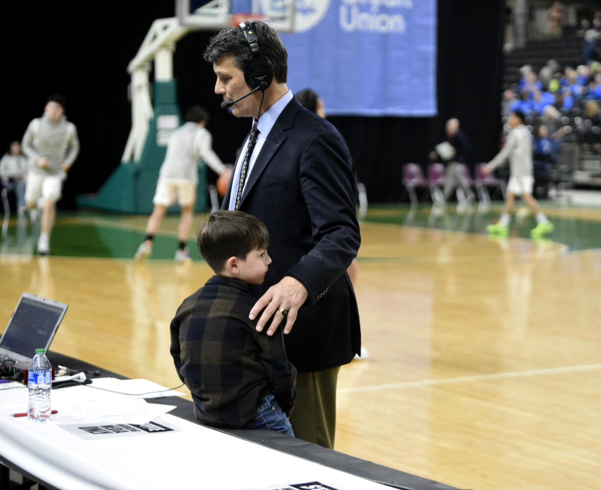 Mark Morris boys basketball coach Bill Bakamus does a radio interview next to his grandson after a 51-47 loss to Bremerton in the Class 2A state tournament Wednesday, Feb. 28, 2024 in Yakima. The round of 12 loss ended the 41-year coaching career for Bakamus.