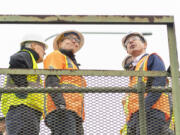 Oregon Gov. Tina Kotek, center, and U.S. Department of Transportation Secretary Pete Buttigieg look up at the Interstate 5 Bridge on Tuesday in Vancouver.