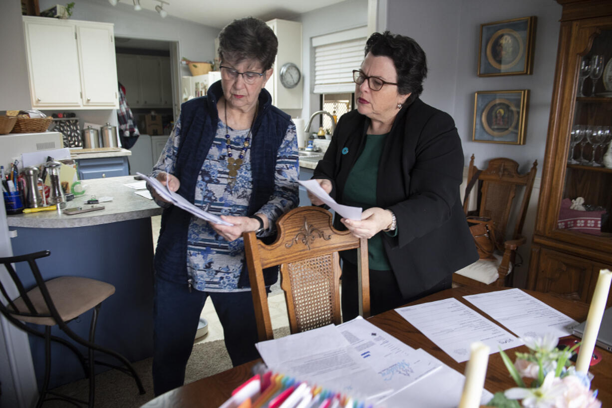 Jayne McCarley, left, a resident of Meadow Verde Mobile Home Park, looks over paperwork including her rent increase notice with fellow resident Michelle Bart at her Hazel Dell home Monday morning hours before they knew a rent stabilization bill would die.