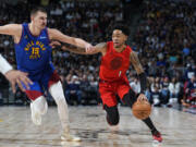 Portland Trail Blazers guard Anfernee Simons, right, drives past Denver Nuggets center Nikola Jokic in the first half of an NBA basketball game Friday, Feb. 2, 2024, in Denver.