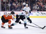 Seattle Kraken's Matty Beniers (10) skates the puck past Philadelphia Flyers' Ryan Poehling (25) during the first period of an NHL hockey game, Saturday, Feb. 10, 2024, in Philadelphia.