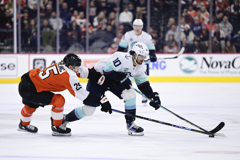 Seattle Kraken's Matty Beniers (10) skates the puck past Philadelphia Flyers' Ryan Poehling (25) during the first period of an NHL hockey game, Saturday, Feb. 10, 2024, in Philadelphia.