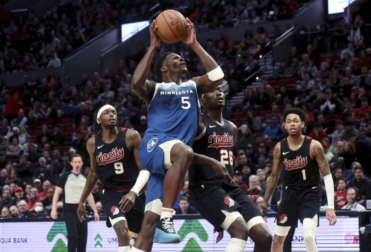 Minnesota Timberwolves guard Anthony Edwards drives to the basket against Portland Trail Blazers forward Jerami Grant, left, and center Duop Reath, second from right, defend and guard Anfernee Simons, right, watches during the second half of an NBA basketball game in Portland, Ore., Thursday Feb. 15, 2024.