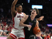 Washington guard Paul Mulcahy (9) drives on Arizona forward Keshad Johnson during the first half of an NCAA college basketball game, Saturday, Feb. 24, 2024, in Tucson, Ariz.