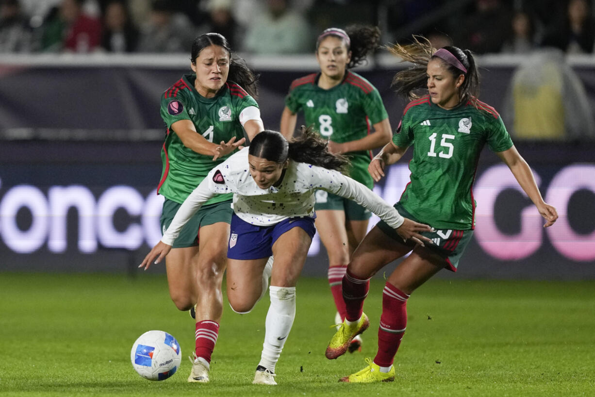 United States forward Sophia Smith, front, falls while vying for the ball against, from back left to right, Mexico defender Rebeca Bernal, midfielder Alexia Delgado and defender Cristina Ferral during a CONCACAF Gold Cup women's soccer tournament match, Monday, Feb. 26, 2024, in Carson, Calif.