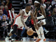 Miami Heat forward Jimmy Butler, left, dribbles around Portland Trail Blazers forward Jerami Grant during the second half of an NBA basketball game in Portland, Ore., Tuesday, Feb. 27, 2024.