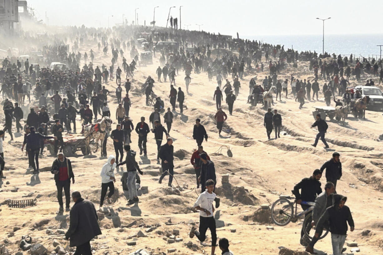 Palestinians wait for humanitarian aid on a beachfront in Gaza City, Gaza Strip, Sunday, Feb. 25, 2024.