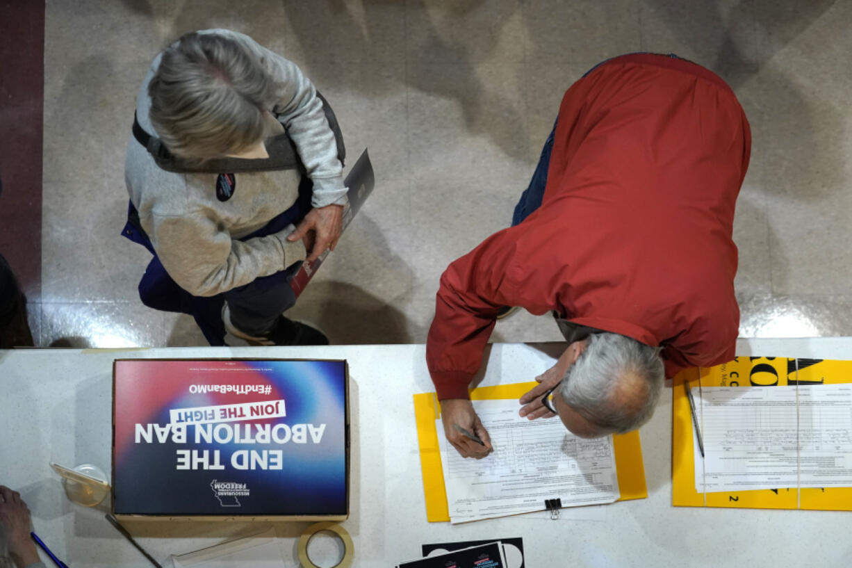 FILE - A residents places his signature on a petition during Missourians for Constitutionals Freedom kick-off petition drive, Feb. 6, 2024 in Kansas City, Mo. Abortion rights advocates are trying to get initiatives to protect reproductive on the ballot in several states this year, and one major difference has emerged in their proposed language &mdash; whether to include mental health as an exception.