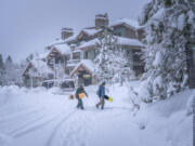 In this photo provided by Mammoth Lakes Tourism, snowboarders walk in the snow on Monday, Feb. 19, 2024, in Mammoth Lakes, Calif.