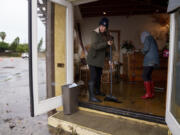 People push out water from a flooded business, Thursday, Feb. 1, 2024 in Seal Beach, Calif. Heavy rain flooded roadways and much-needed snow piled up in the mountains on Thursday as the first of back-to-back atmospheric rivers pummeled California.