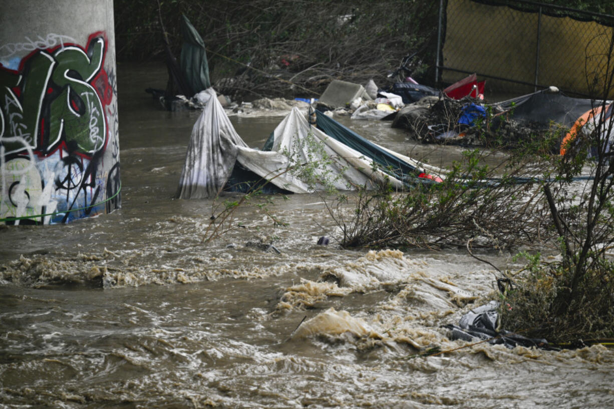 Rising waters caused by heavy rain destroy encampments along the Santa Ana River near Van Buren Street in Riverside, Calif., on Monday, Feb. 5, 2024.