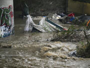 Rising waters caused by heavy rain destroy encampments along the Santa Ana River near Van Buren Street in Riverside, Calif., on Monday, Feb. 5, 2024.