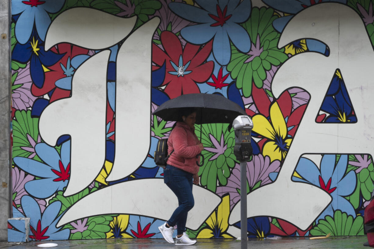 A woman walk under the rain in Los Angeles, Monday, Feb. 19, 2024.